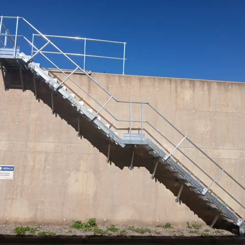 ista lateral del conjunto: escalera fija con barandilla y plataforma superior de acceso.